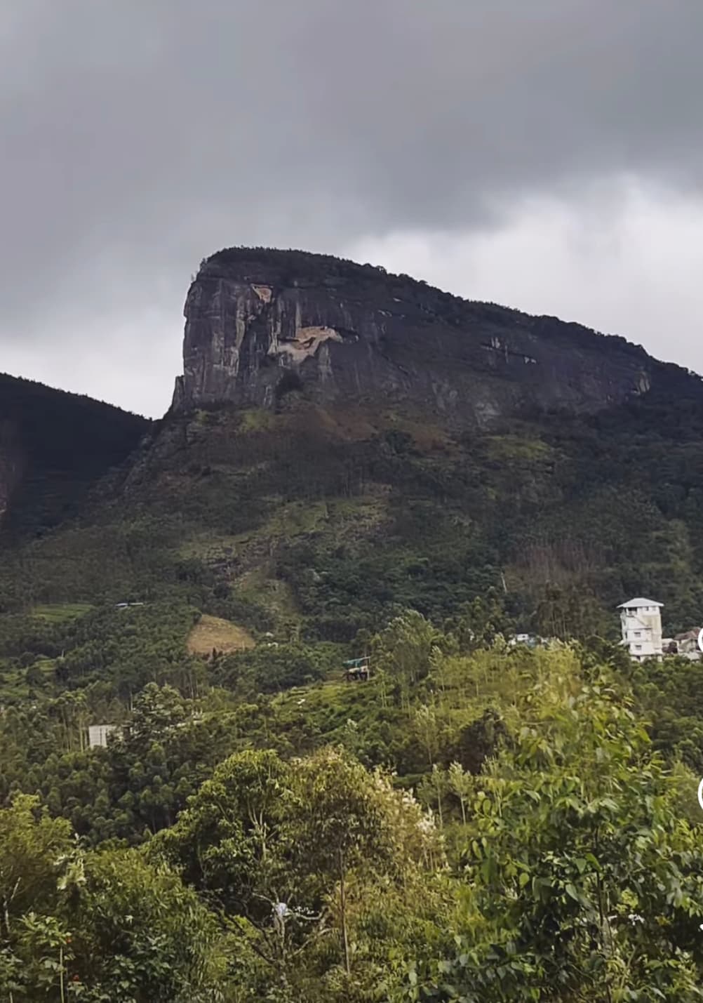 A dramatic rock face rising above forested hills near Kanthalloor