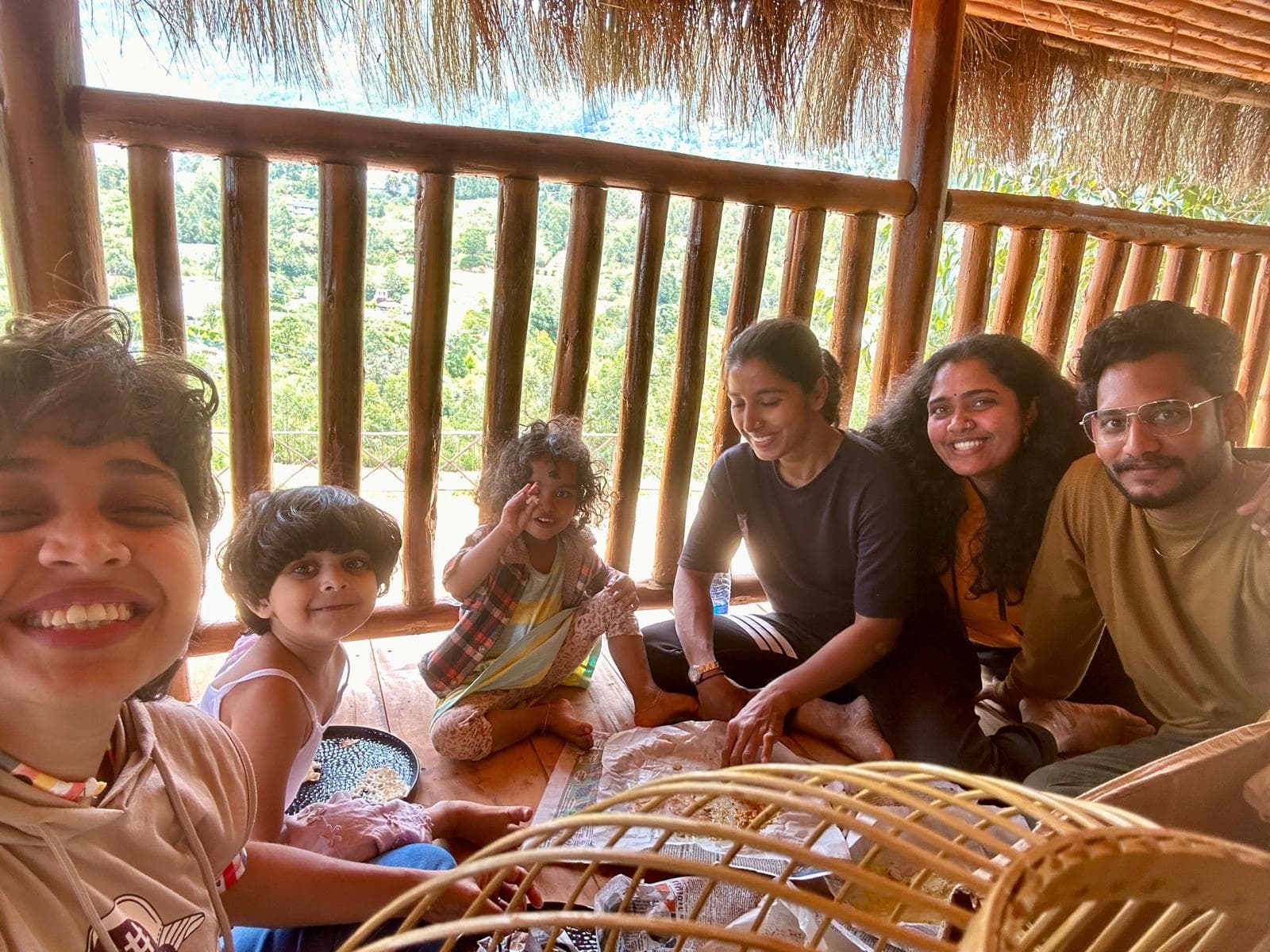 Friends and children relaxing on a thatched verandah