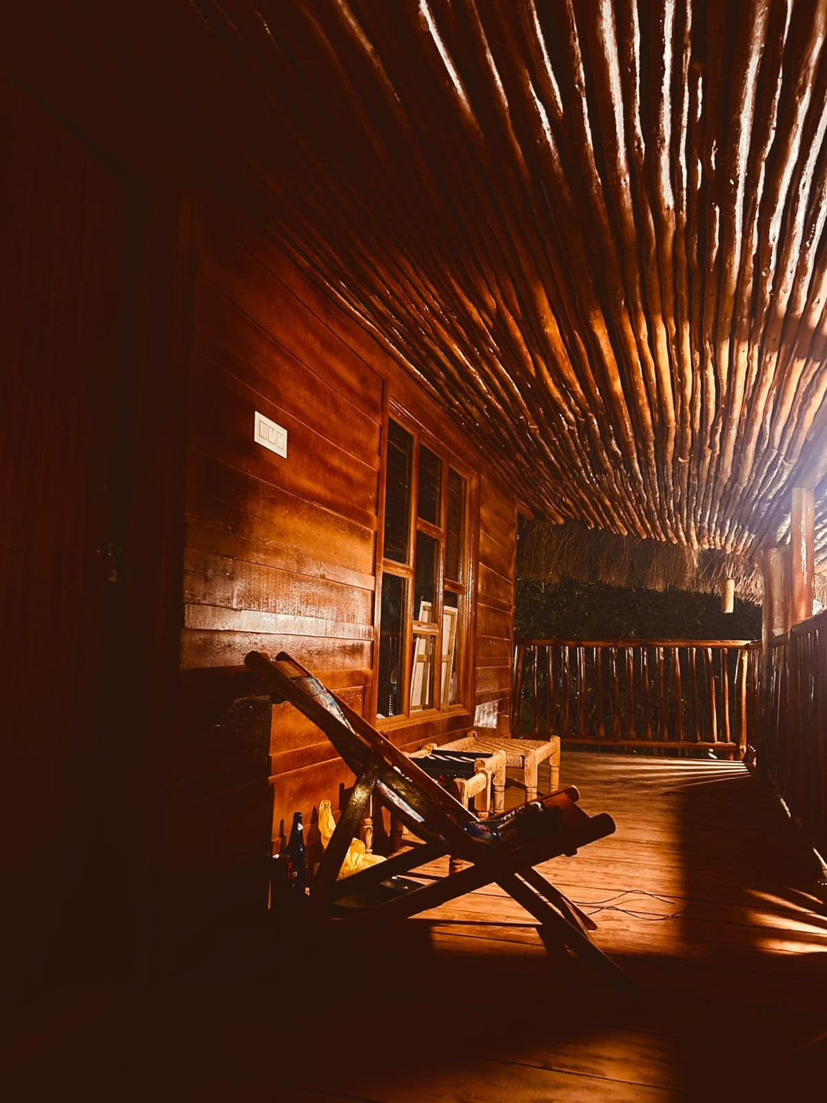 A timber verandah glowing in warm evening light, with a reclining wooden chair